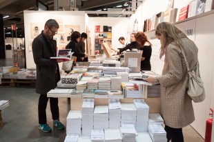 Several customers browse a table of books