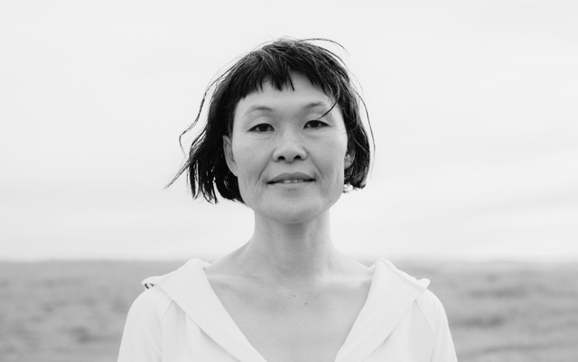 a black and white head and shoulders portrait picture of artist Yumi Umiumare.