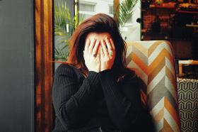 rejection. image is of a woman with dark hair and her face covered by her hands as she deals with creative rejection.
