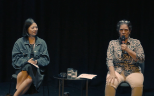 Still from recording of feature writing workshop at The Channel - Arts Centre Melbourne. Two women are sitting on stage against a black backdrop. On the left is Celina, an Asian Australian woman in her mid-20s with a black bob, denim jacket and black dress. On the right is Madeleine, a middle aged Caucasian woman wearing a blue and white floral shirt and white pants.