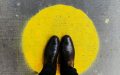 Photo: Jon Tyson, Unsplash. A pair of black shoes standing on top of a yellow circle spray painted onto the concrete.