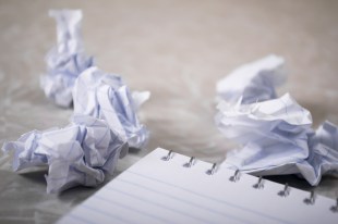 writers' block. Image is a close-up of an empty notepad and some scrumpled up sheets of paper.