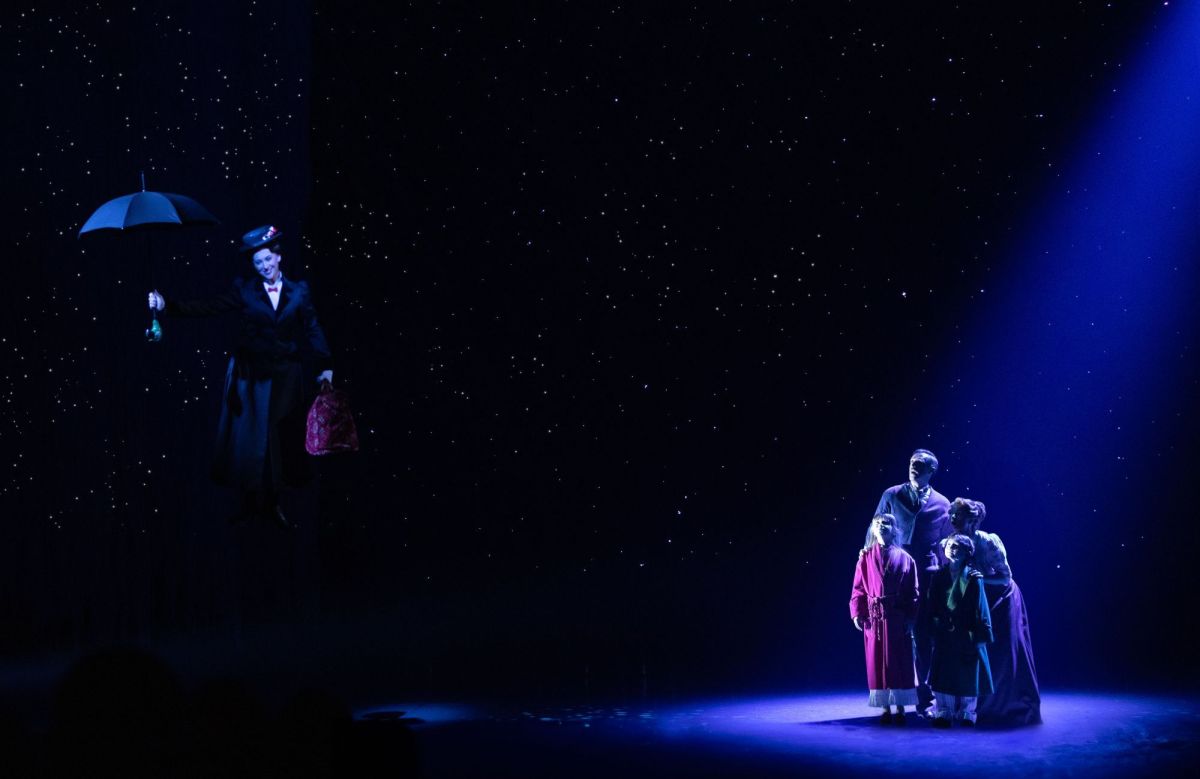 A scene from the stage musical 'Mary Poppins', showing the titular character flying away with her umbrella, as the Banks family look on from the stage.