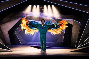 A black man in a turquoise tracksuit with wings on in The Boy with Wings.